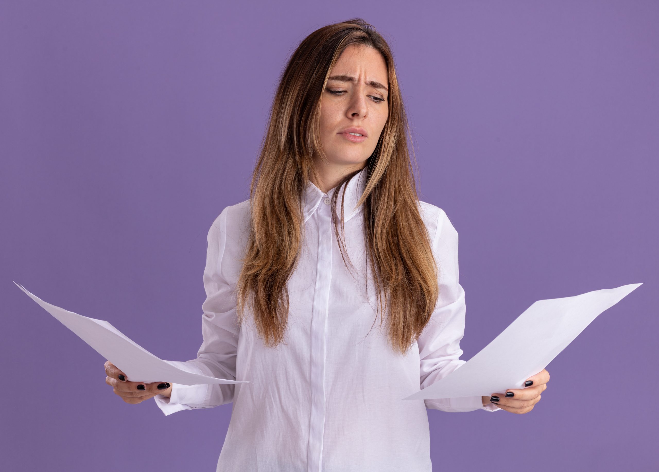 A concerned woman in a white shirt stands against a purple background, holding two sheets of paper and looking confused. Her expression suggests she is evaluating difficult choices, possibly related to cutting fixed expenses in a financial decision-making process.