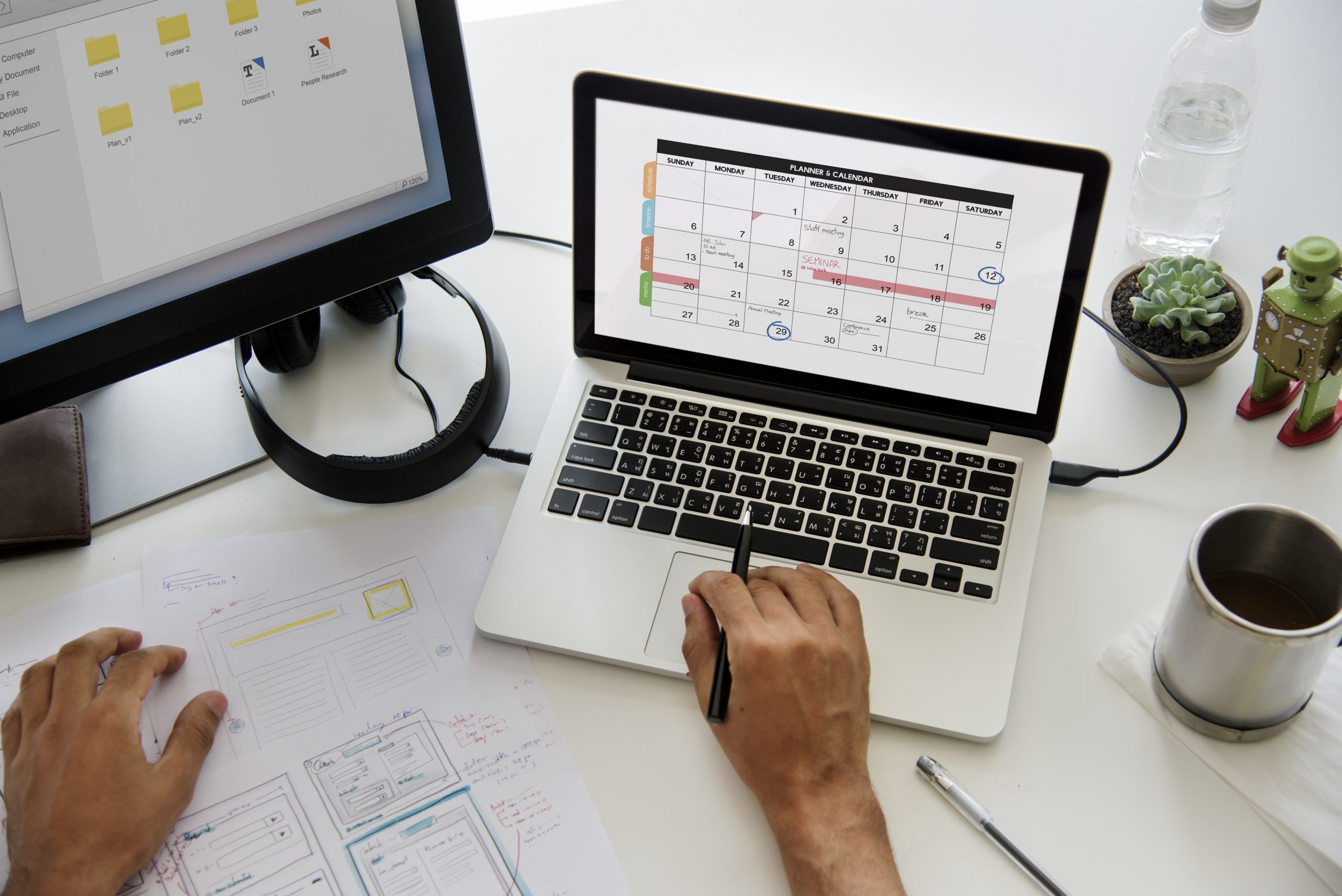 A person works at a modern desk with a laptop displaying a digital calendar, papers with diagrams, and financial notes, representing strategic planning to organize your finances effectively and stay on top of important deadlines.